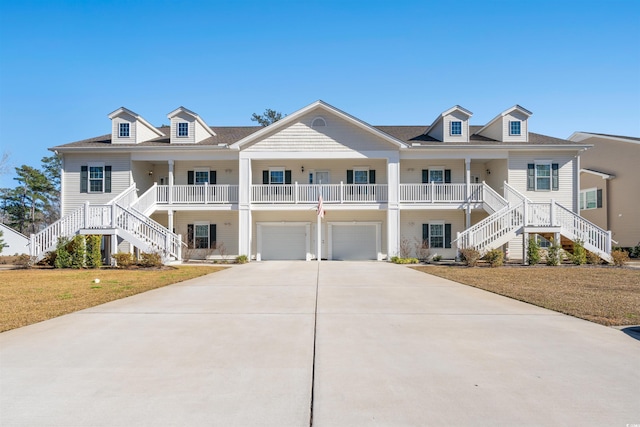 coastal home featuring a front yard, driveway, stairway, and an attached garage