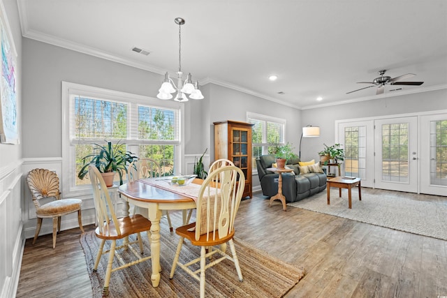 dining space with wainscoting, crown molding, and light wood-style flooring