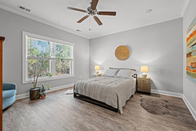 bedroom with baseboards, crown molding, visible vents, and wood finished floors