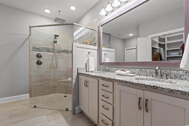 full bath with tiled shower, a sink, and double vanity