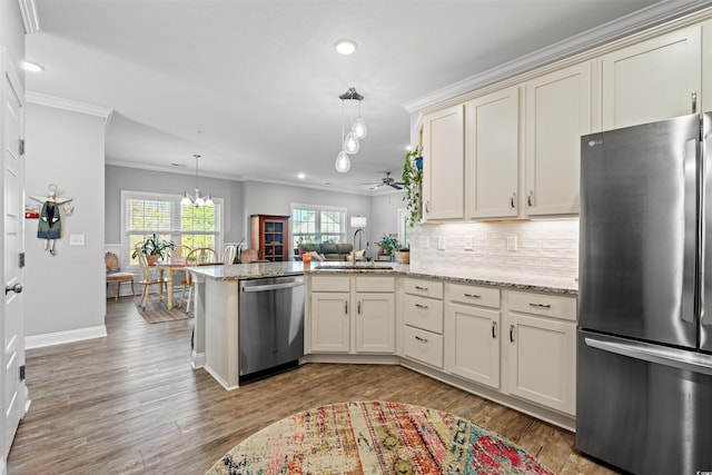 kitchen featuring stainless steel appliances, light wood-type flooring, a peninsula, and a sink