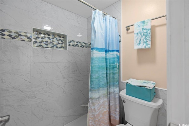 full bathroom featuring toilet, wainscoting, and a tile shower