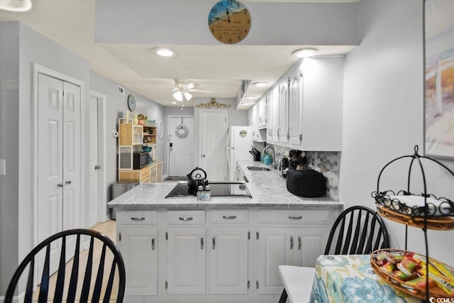 kitchen featuring white cabinetry, black electric cooktop, a peninsula, and a ceiling fan