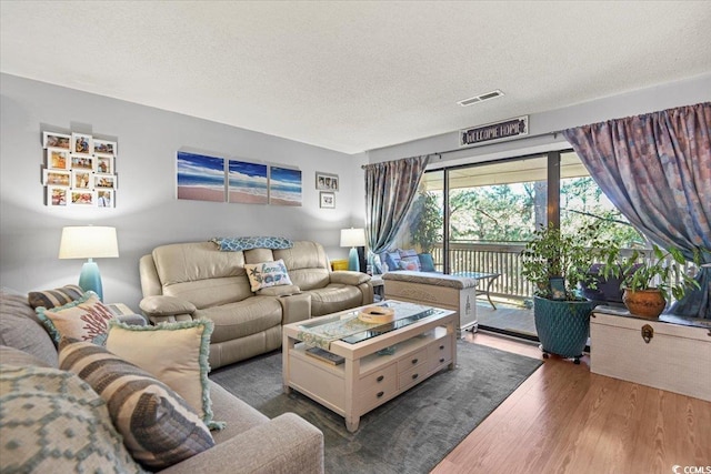 living area with a textured ceiling, visible vents, and wood finished floors