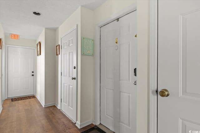 entrance foyer with baseboards, a textured ceiling, and wood finished floors