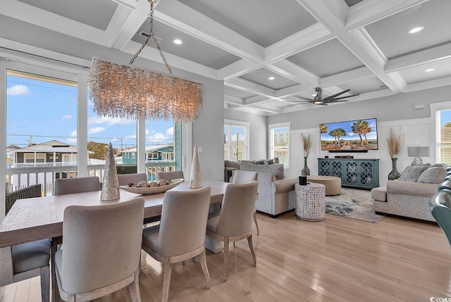 dining space with beamed ceiling, plenty of natural light, and light wood-style floors