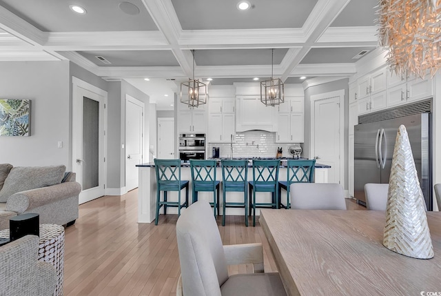 interior space with light wood-type flooring, coffered ceiling, and beam ceiling