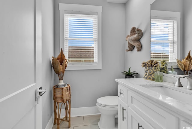 half bath featuring tile patterned floors, vanity, toilet, and baseboards