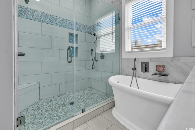 full bathroom featuring a stall shower, tile patterned flooring, a freestanding bath, and tile walls