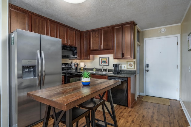 kitchen featuring dark countertops, black appliances, light wood-style flooring, and a textured ceiling