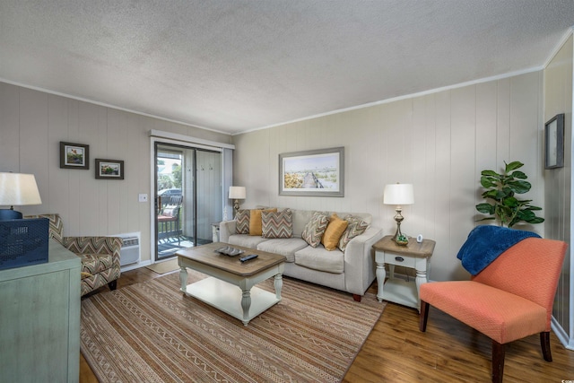 living room featuring a wall unit AC, a textured ceiling, ornamental molding, and wood finished floors