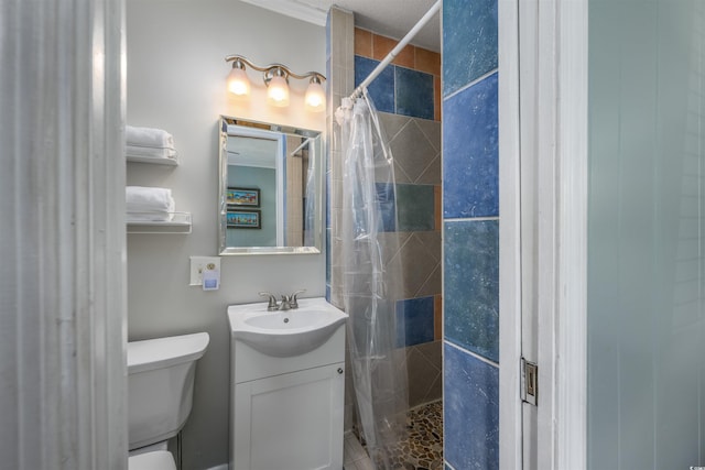 bathroom featuring toilet, tiled shower, and vanity