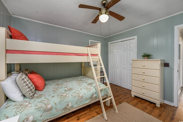 bedroom featuring a closet, ornamental molding, ceiling fan, a textured ceiling, and wood finished floors