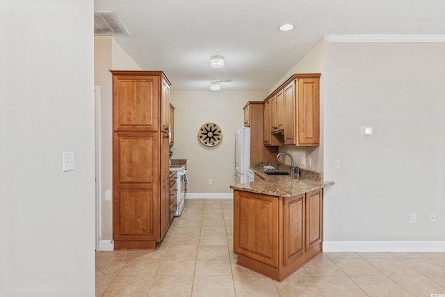 kitchen featuring brown cabinetry, white appliances, visible vents, and light stone countertops