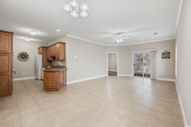 unfurnished living room featuring ceiling fan with notable chandelier, ornamental molding, and baseboards