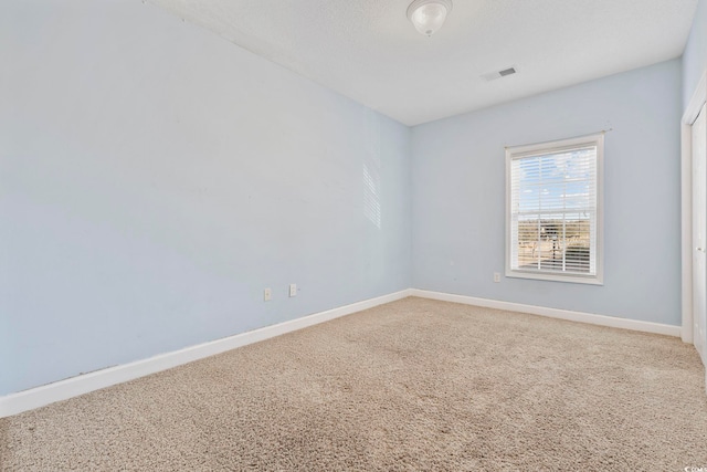 unfurnished room with light carpet, visible vents, and baseboards