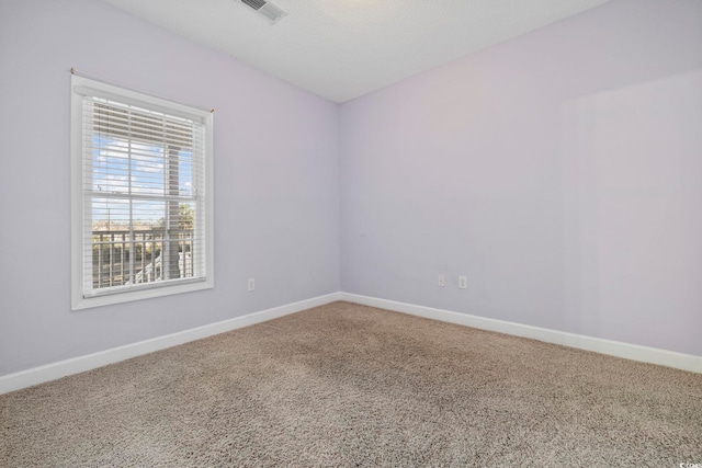 carpeted empty room featuring visible vents, a textured ceiling, and baseboards