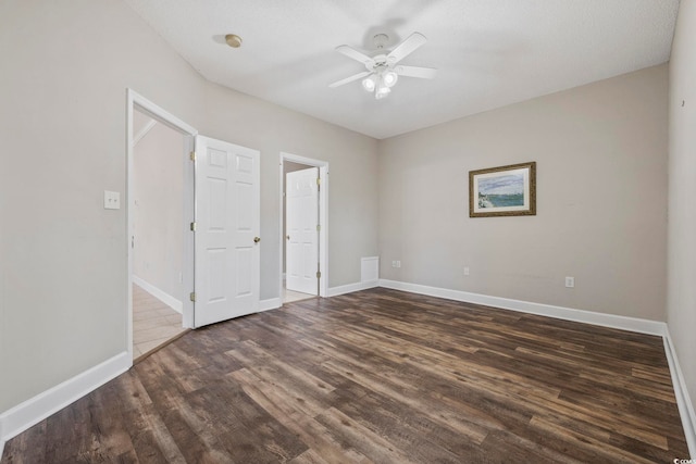 unfurnished bedroom featuring ceiling fan, baseboards, and dark wood-type flooring