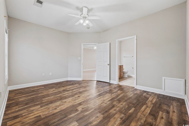 unfurnished bedroom with ceiling fan, wood finished floors, visible vents, baseboards, and ensuite bath