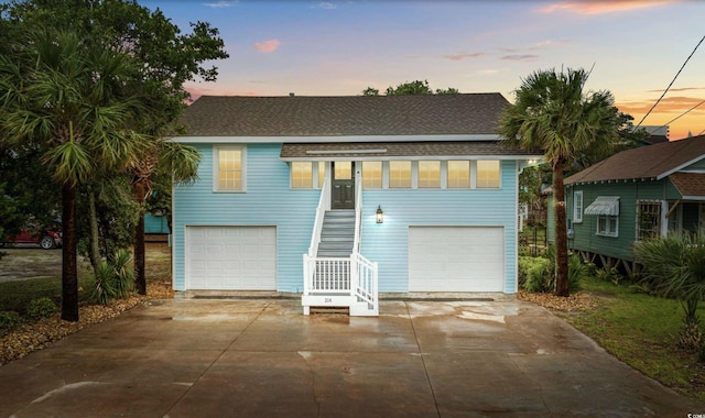 214 2nd Ave S, North Myrtle Beach, SC 29582 - view of front facade featuring stairs, a shingled roof, driveway, and a garage