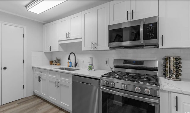 214 2nd Ave S, North Myrtle Beach, SC 29582 - kitchen featuring appliances with stainless steel finishes, tasteful backsplash, white cabinetry, and light wood-style flooring