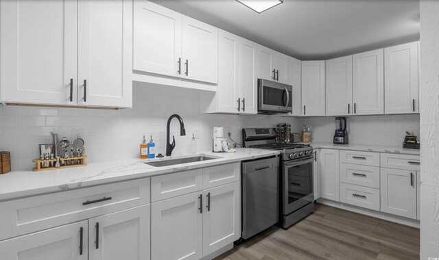 214 2nd Ave S, North Myrtle Beach, SC 29582 - kitchen featuring stainless steel appliances, white cabinets, decorative backsplash, light stone countertops, and wood finished floors