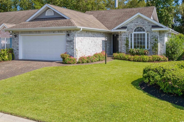 ranch-style house with a front lawn, decorative driveway, a garage, and roof with shingles