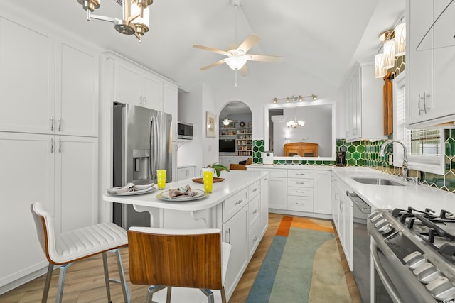 kitchen featuring white cabinetry, light countertops, a sink, lofted ceiling, and stainless steel appliances