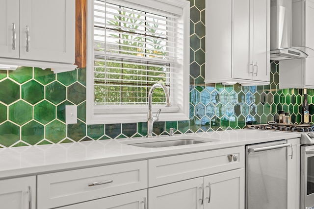 kitchen featuring tasteful backsplash, wall chimney range hood, light countertops, stove, and a sink