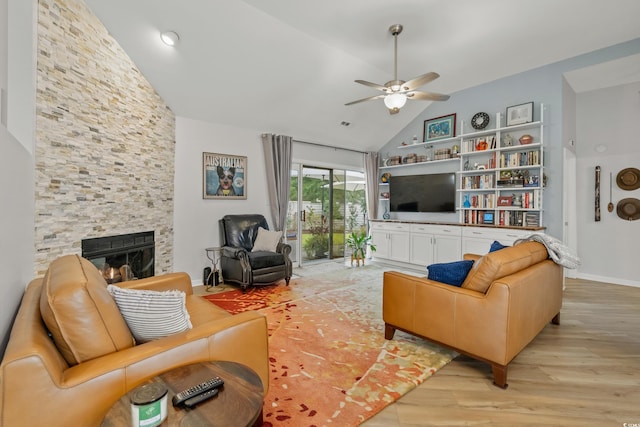 living area featuring baseboards, a ceiling fan, a fireplace, light wood finished floors, and high vaulted ceiling