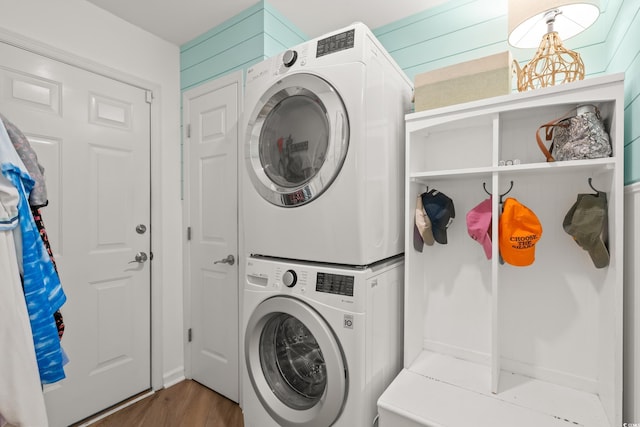 laundry area with stacked washing maching and dryer, laundry area, and wood finished floors