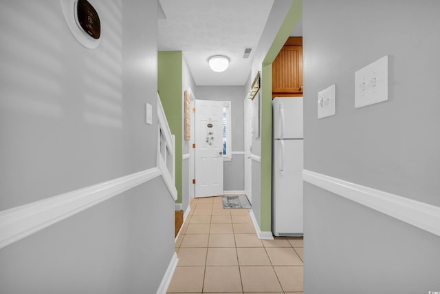 hallway with light tile patterned floors, visible vents, baseboards, stairs, and a textured ceiling