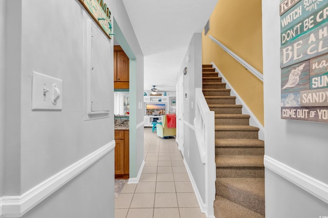 stairway with tile patterned flooring, ceiling fan, and baseboards