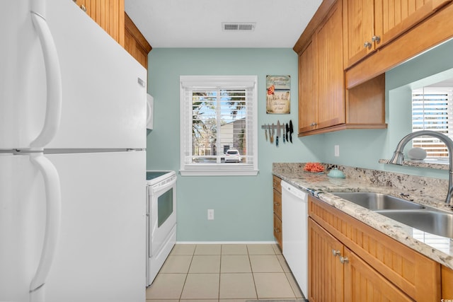 kitchen with visible vents, light tile patterned flooring, a sink, white appliances, and baseboards