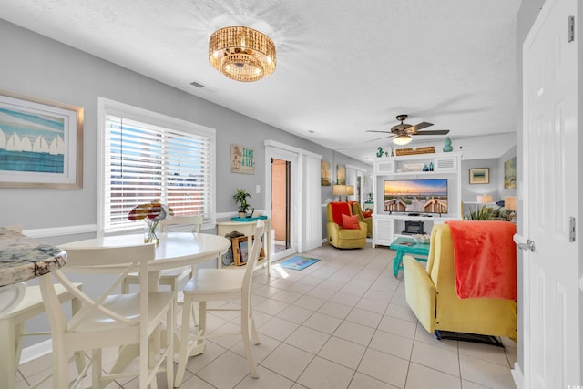 living room featuring a ceiling fan, visible vents, a textured ceiling, and light tile patterned flooring