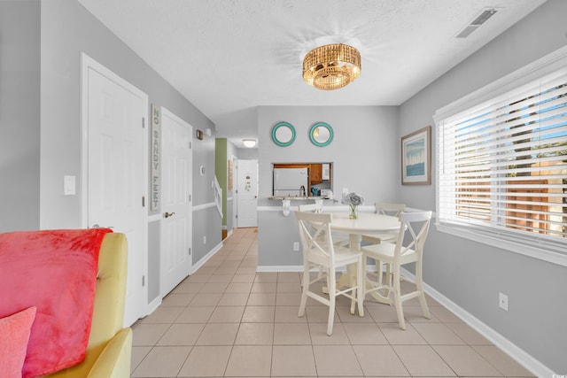 dining space featuring light tile patterned flooring, visible vents, baseboards, and a textured ceiling