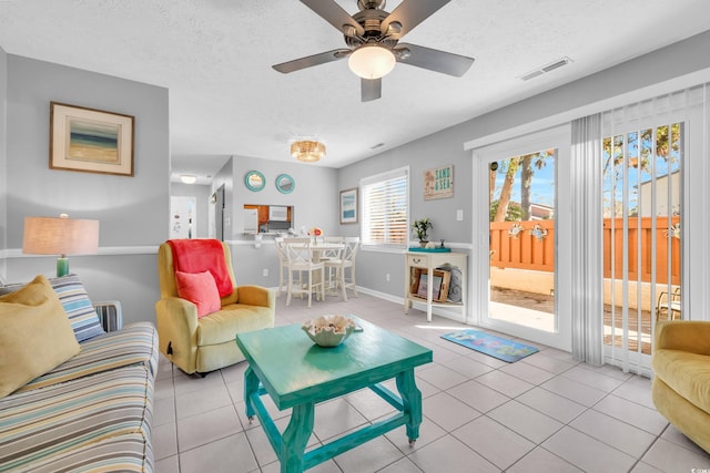 tiled living room with a ceiling fan, baseboards, visible vents, and a textured ceiling