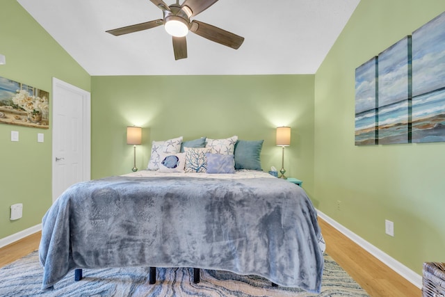 bedroom featuring a ceiling fan, lofted ceiling, baseboards, and wood finished floors