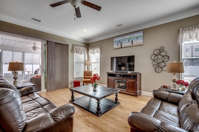 living room with a healthy amount of sunlight, light wood-style floors, visible vents, and ornamental molding