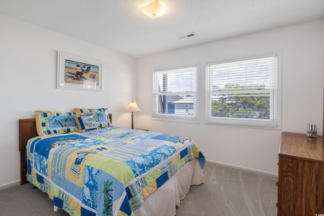 carpeted bedroom featuring baseboards, visible vents, and a textured ceiling