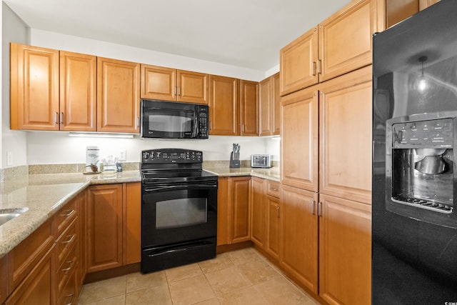 kitchen featuring black appliances, light stone countertops, and light tile patterned floors