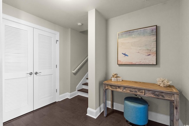 hallway featuring dark wood-type flooring, baseboards, and stairway