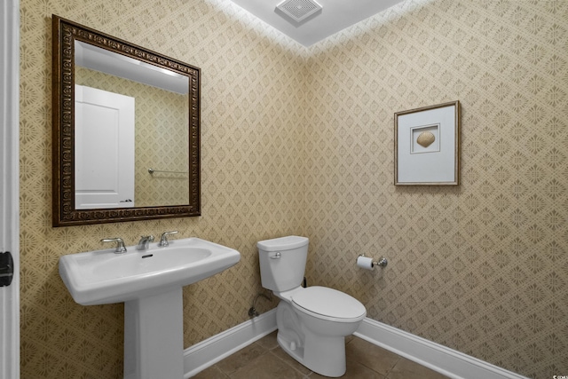 bathroom featuring baseboards, toilet, and tile patterned flooring