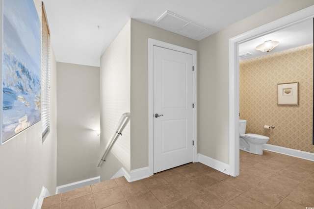 bathroom featuring toilet, baseboards, and wallpapered walls