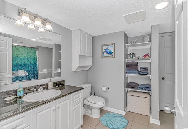 bathroom with a textured ceiling, vanity, tile patterned flooring, and toilet