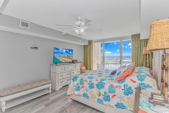 bedroom with visible vents, ceiling fan, wood finished floors, access to exterior, and a textured ceiling