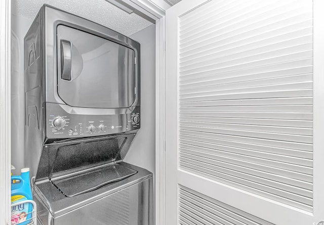 laundry room with laundry area, a textured ceiling, and stacked washer / drying machine