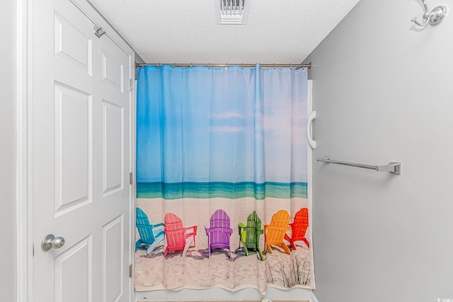 bathroom featuring curtained shower, visible vents, and a textured ceiling