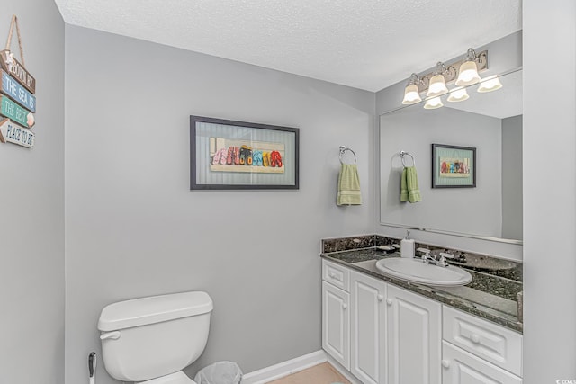 bathroom with toilet, baseboards, a textured ceiling, and vanity