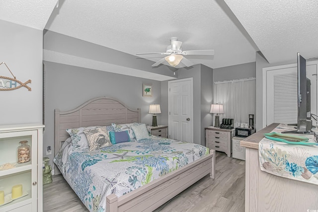 bedroom featuring a textured ceiling, ceiling fan, and light wood finished floors